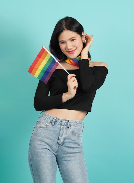 Portret van een jong meisje met een LGBT-vlag staande tegen een blauwgroene studio als achtergrond