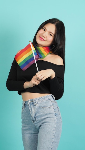 Portret van een jong meisje met een LGBT-vlag staande tegen een blauwgroene studio als achtergrond