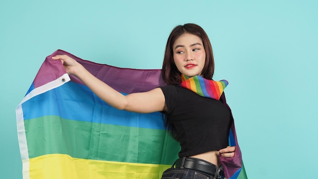 Portret van een jong meisje met een lgbt-vlag staande tegen een blauwgroene studio als achtergrond