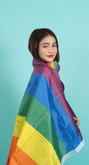 Portret van een jong meisje met een LGBT-vlag staande tegen een blauwgroene studio als achtergrond