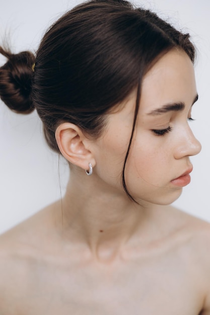 Portret van een jong meisje met een schone huid zonder make-up, stijlvol minimalisme en meisjesachtige schoonheid