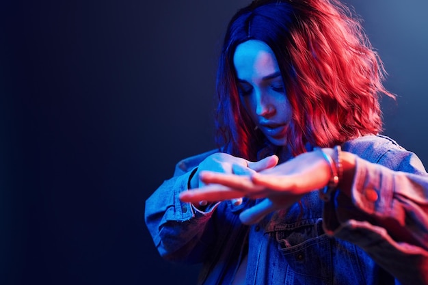 Portret van een jong meisje met krullend haar dat danst in rood en blauw neon in de studio