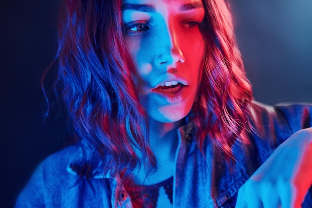 Portret van een jong meisje met krullend haar in rood en blauw neon in studio