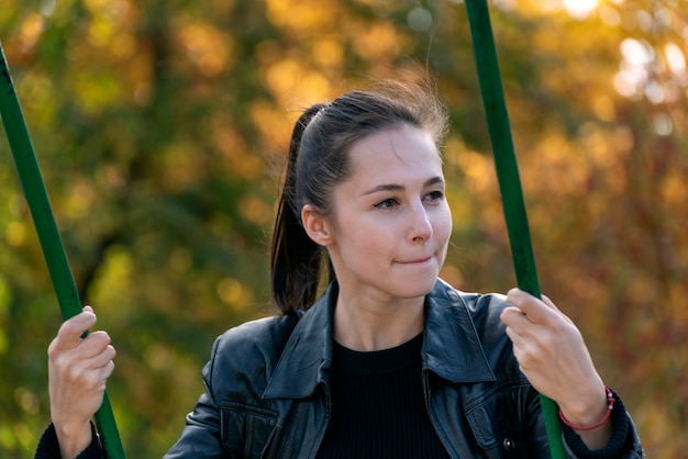 Portret van een jong meisje op schommel op de oppervlakte van het de herfstpark