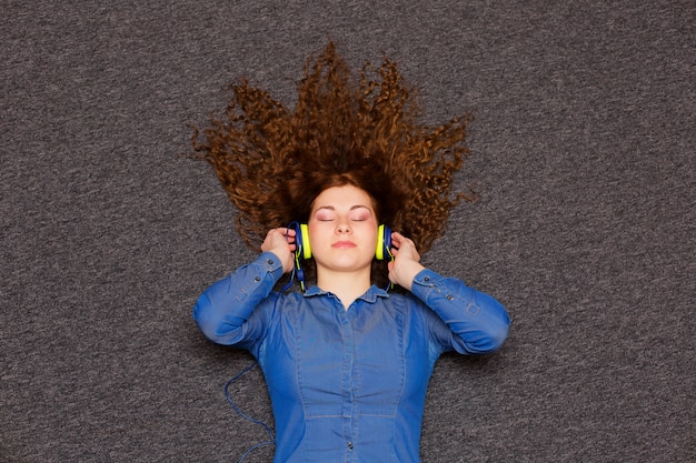 Foto portret van een jong mooi meisje in hoofdtelefoons die van muziek genieten