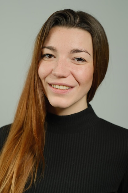 Portret van een jong mooi meisje met lang rood haar in zwarte broek en een trui die in de studio poseert