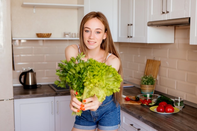 portret van een jong mooi meisje met slabladeren in de keuken