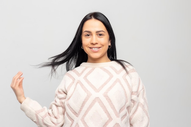 Portret van een jong mooi schattig brunette meisje in een warme wintertrui op een lichtgrijze achtergrond