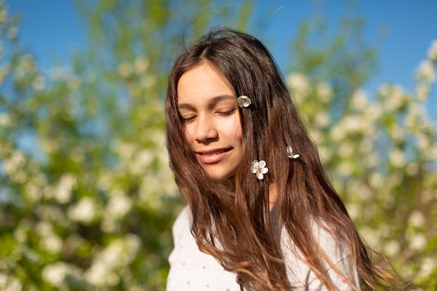 Portret van een jong mooi tienermeisje in een bloeiende de lente groene tuin.