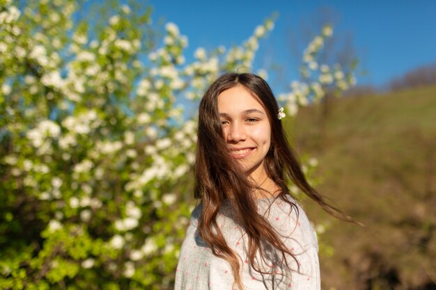 Portret van een jong mooi tienermeisje in een bloeiende de lente groene tuin.