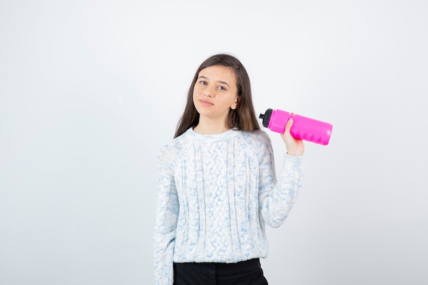 Portret van een jong schattig meisje in trui met roze waterfles.