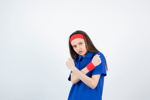 Portret van een jong sportief meisje dat en gekruiste wapens bevindt zich toont