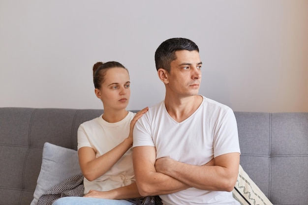 Portret van een jong stel met een conflict beledigde man die op de bank zit en zich afwendt van de vrouw die familieruzie of ruzie heeft, lijden aan misverstanden