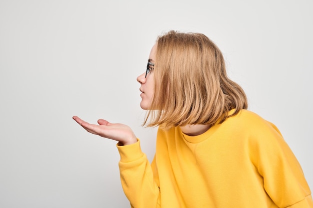 Portret van een jong studentenmeisje dat luchtkusjes verzendt geïsoleerd op een witte studioachtergrond