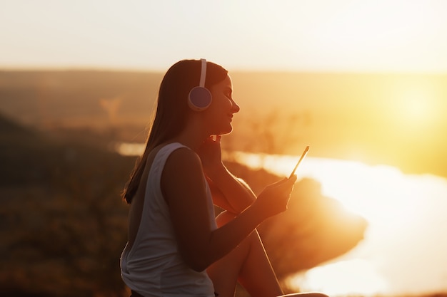 Portret van een jong teder meisje geniet van haar weekenden in de natuur en luistert naar muziek via een koptelefoon.