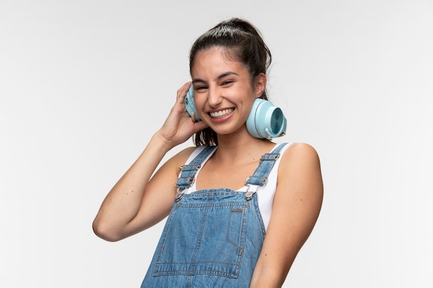 Foto portret van een jong tienermeisje in een overall die op muziek op haar koptelefoon schommelt