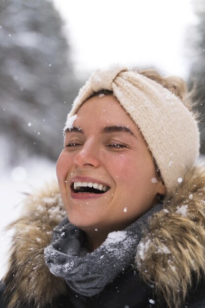 Portret van een jong vrolijk meisje dat geniet van sneeuwval tijdens een mooie winterdag