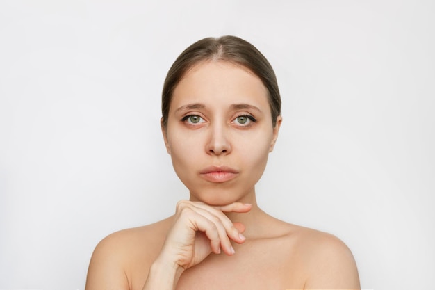 Portret van een jonge aantrekkelijke blanke blonde vrouw met make-up die haar hand onder de kin houdt