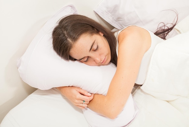 Portret van een jonge aantrekkelijke vrouw met lang haar die in haar bed slaapt