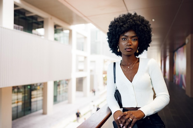 Portret van een jonge Afrikaanse vrouw met een afro-kapsel die op het balkon staat en poseert?