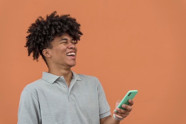 Portret van een jonge Afro-Amerikaanse man die lacht en naar zijn telefoon kijkt