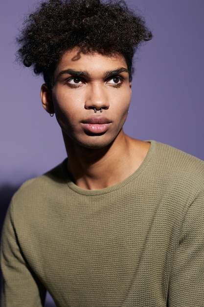 Portret van een jonge Afro-Amerikaanse transgender man met afro kapsel en casual kleding in studio