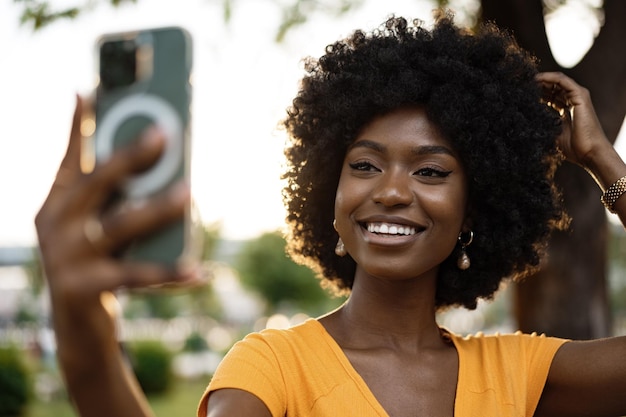 Portret van een jonge Afro-Amerikaanse vrouw die buiten een selfie neemt