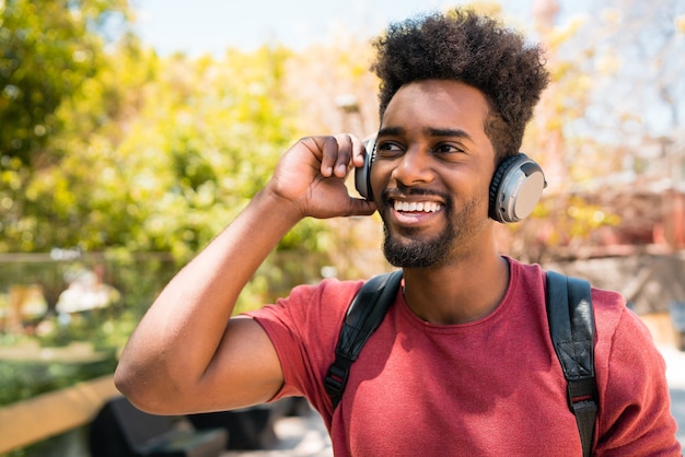 Portret van een jonge afro man genieten van en luisteren naar muziek met een koptelefoon. Technologie en levensstijlconcept.