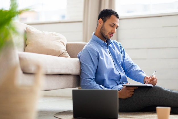 Portret van een jonge Arabische man die laptop gebruikt en schrijft