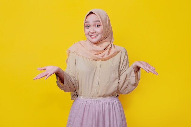 Portret van een jonge aziatische dame die lacht met een vrolijke uitdrukking, laat iets geweldigs zien in een casual doek over een gele muur
