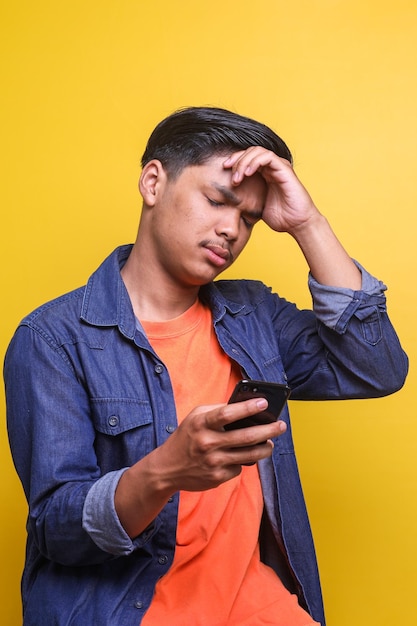 Portret van een jonge Aziatische man geschokt en verdrietig om slecht nieuws op zijn telefoon te zien alsof hij door een meisje wordt gedumpt