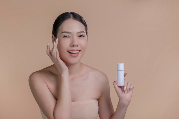 Portret van een jonge Aziatische vrouw die lacht met mockup product voor reclametekst plaats beige achtergrond Concept van gezondheidszorg voor huidschoonheidsverzorgingsproduct voor reclame
