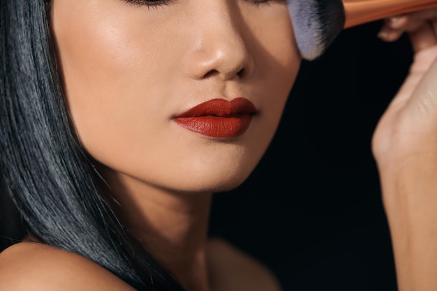 Portret van een jonge Aziatische vrouw die lippenstift aanbrengt