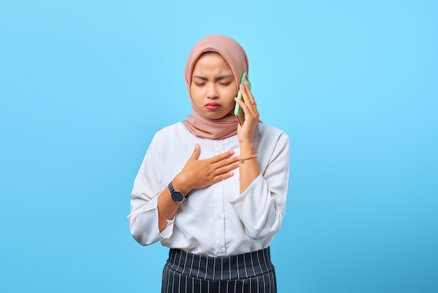 Portret van een jonge Aziatische vrouw die op een mobiele telefoon praat met een andere hand op de borst