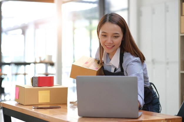 Portret van een jonge Aziatische vrouw KMO die thuis met een doos werkt op de werkplek start-up eigenaar van een klein bedrijf ondernemer van een kleinschalig of freelance bedrijf online en bezorgconcept