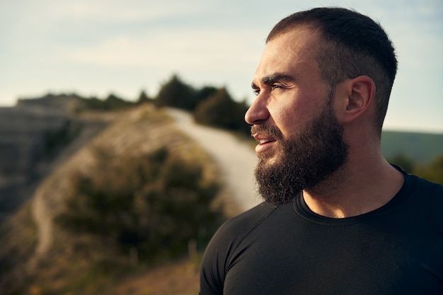 Portret van een jonge, bebaarde man buiten in de bergen