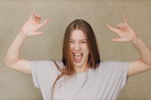 Portret van een jonge blanke vrouw die naar de camera kijkt tegen een beige achtergrond