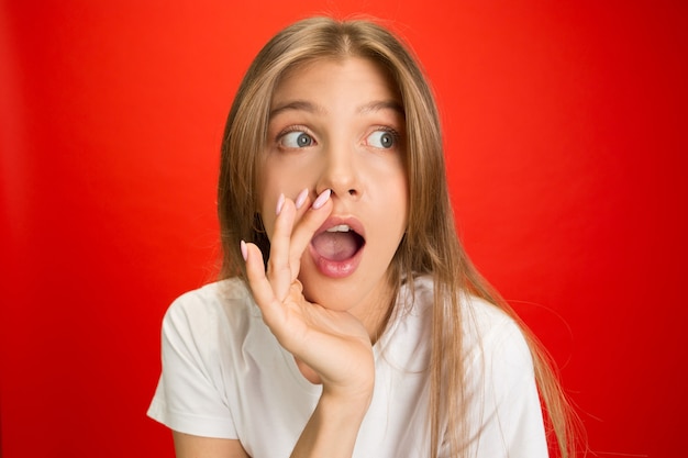 Portret van een jonge blanke vrouw met heldere emoties op een felrode muur