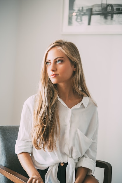 Portret van een jonge blonde vrouwenzitting