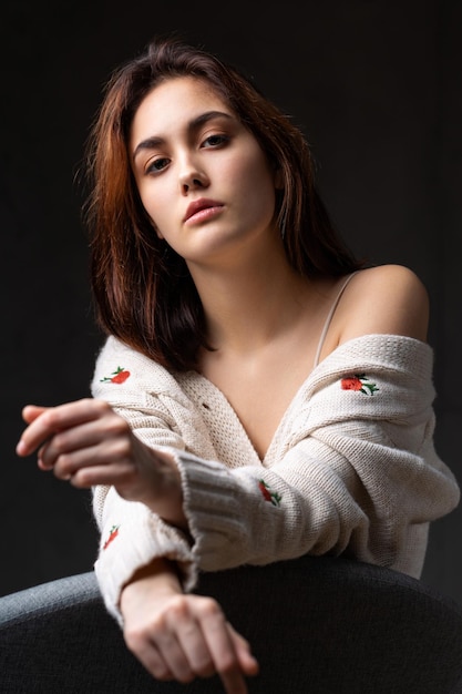 Portret van een jonge brunette met lang haar in de studio Dramatische foto in donkere kleuren