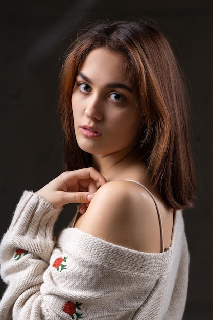 Portret van een jonge brunette met lang haar in de studio Dramatische foto in donkere kleuren