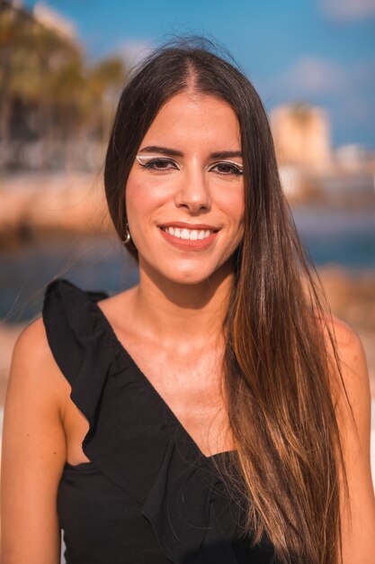 Portret van een jonge brunette vrouw die geniet van haar dag aan de kust aan het strand