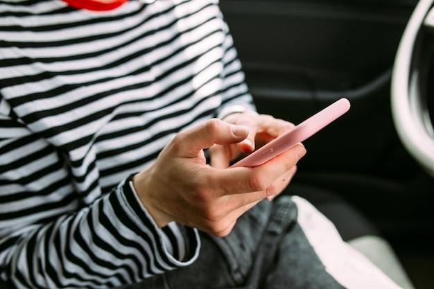 Portret van een jonge brunette vrouw die in een auto rijdt met een smartphone