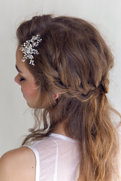 Portret van een jonge brunette vrouw in een lange witte jurk op een witte achtergrond