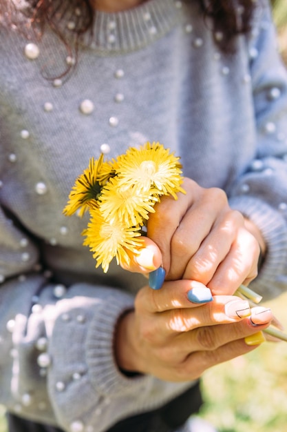 Portret van een jonge brunette vrouw in het voorjaar in een park met paardebloemen