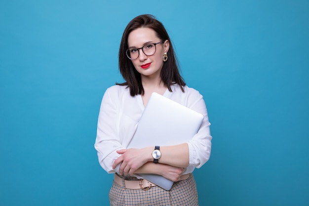 Portret van een jonge brunette vrouw met een laptop op een blauwe achtergrond