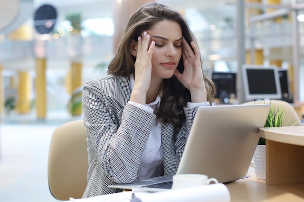 Portret van een jonge brunette zakenvrouw met behulp van laptop op kantoor.