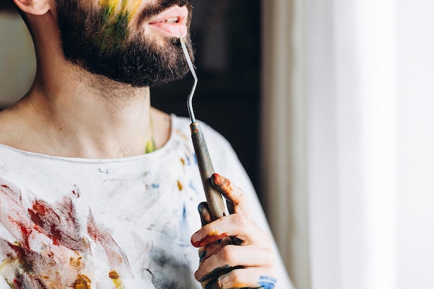 Portret van een jonge creatieve kunstenaar die een wit T-shirt draagt met gekleurde vlekken van verf