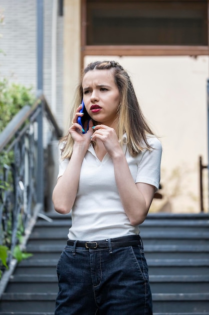 Portret van een jonge dame die bij de trap staat en aan de telefoon praat