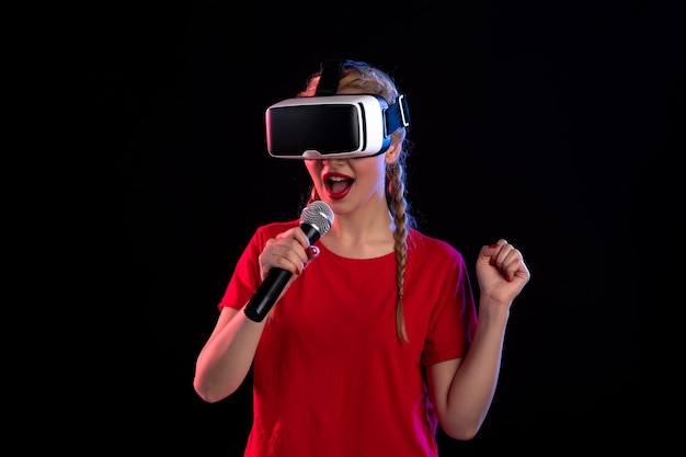 Portret van een jonge dame die vr speelt en zingt op een donkere muur